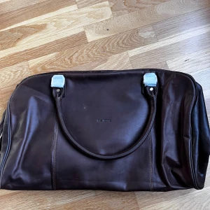 Nyskick The Monte Brun skinnväska medium - Säljer en stilren brun skinnväska från The Monte. Väskan har två handtag och en diskret logotyp på framsidan. Perfekt för dig som gillar klassisk design och hög kvalitet. Passar utmärkt för både vardag och resa. Väskan är sprillans ny, aldrig använts. Endast legat i garderoben i nått år. Nypris 2699:-