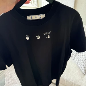 Svart t-shirt från Off-White - Snygg svart t-shirt från Off-White med tryck på både fram- och baksidan. Framsidan har Off-White-loggan i vitt och baksidan har ett unikt konstnärligt mönster i grått. Perfekt för dig som vill ha en stilren men ändå iögonfallande look.