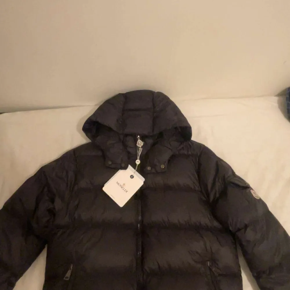 Säljer en snygg svart dunjacka från Moncler med huva och dragkedja. Jackan har en Moncler-logga på ärmen och praktiska fickor med knappar. Perfekt för kyliga dagar! Den är aldrig använt i storlek s säljer den på grund av i fel storlek för mig!. Takit.