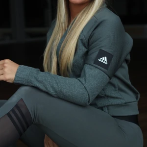 Grön hoodie från Adidas - Snygg grön hoodie från Adidas med dragkedja och ribbade muddar. Perfekt för en sportig look eller en avslappnad dag. Den har en diskret logga på ärmen och en bekväm passform. Säljs inte längre💚