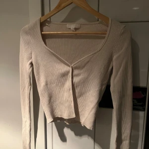 Beige ribbad tröja - Säljer en stilren beige ribbad tröja med v-ringning. Tröjan har långa ärmar och passar perfekt till både jeans och kjol.  Den är från H&M❤️