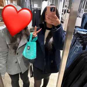 Svart kappa från Design by Si - Säljer en stilren svart kappa från Design by Si i storlek XXS/S. Den har en klassisk dubbelknäppning med stora knappar och en snygg krage. Perfekt för höst och vinter, och ger en elegant touch till vilken outfit som helst. Kappan är i bra skick och redo för nya äventyr!