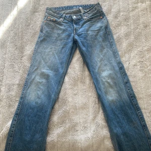 Blå jeans - Säljer ett par klassiska blå jeans i en snygg tvätt. De har en rak passform och är perfekta för vardagsbruk. Jeansen har fickor både fram och bak samt knappar och dragkedja i gylfen.
