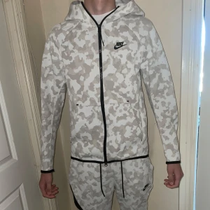 Vit och grå camouflagemönstrad jacka från Nike - Säljer nike tech tracksuit i bra skick. Byxorna är storlek s och tröjan i xs, tröjan passar i s