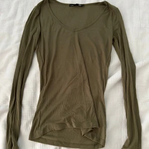 Olivgrön ribbad tröja från 157 - Säljer en olivgrön ribbad tröja från Lager 157 i storlek S. Tröjan har en v-ringad hals och långa ärmar.