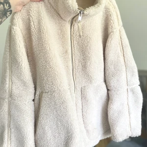 Beige teddyjacka med dragkedja - Supermysig beige teddyjacka som är perfekt för kyliga dagar. Den har en dragkedja framtill och två praktiska fickor. Jackan är långärmad och har en avslappnad passform. Perfekt för höst och vinter! Är i bra skick.