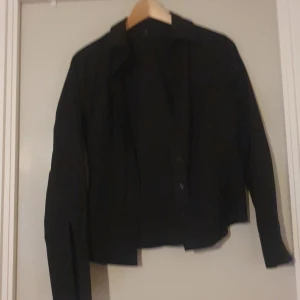 Svart jacka - Säljer en stilren svart skjorta med långa ärmar. Perfekt för har en klassisk design och är lätt att matcha med olika outfits.