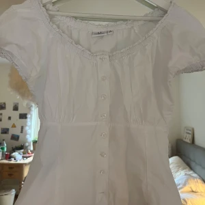Supersöt vit blus - Jättesöt vit blus med knappar puffärmar o spets längst halsen och ärmarna<3 aldrig använd, säljes pga lite stor i bysten för mig!