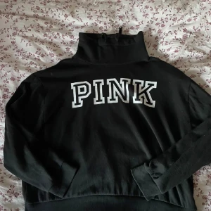 Svart tröja med texten PINK - Läs info 💕💕Säljer en svart tröja med hög krage och texten 'PINK' i vitt på framsidan. Tröjan är långärmad och ser riktigt mysig ut för kyligare dagar. Är nopprig men inte något man ser på långt hål kan skicka bättre bilder sen har den en liten fläck