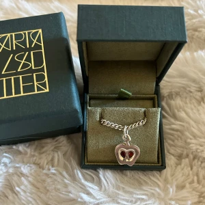 Maria Nilsdotter halsband  - Maria Nilsdotter ”kompis” halsband, äpplet. Fint skick, lite grå på baksidan. Tjock kedja 45 cm i silver. 