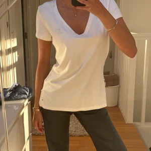 Tommy Hilfiger tshirt  - Tommy Hilfiger tshirt med stenar som logga och även orginal loggan längst ned på höften. Helt oanvänd. Prislapp sitter kvar (köptes för 300 kr) 