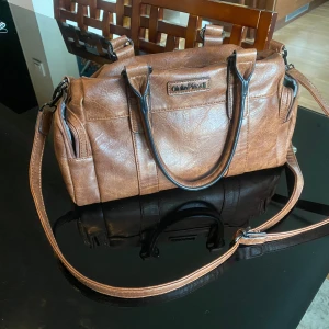 Axelremsväska/Duffel bag i läder - Väldigt praktisk väska med många fickor gjord av läder. Knappt använd och i väldigt bra skick. Användbar för skolan samt utgångar. 