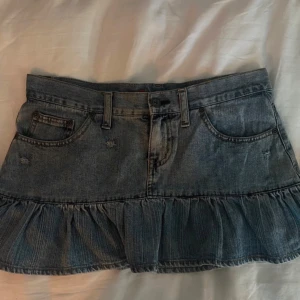 Lågmidjad jeans kjol - Lågmidjad kort volang denim kjol från fishbone i storlek S (36). 