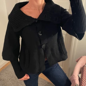 Svart kofta - Svart tjock kofta med trekvartsärmar och insydda långa armar. Hög krage, går att ha på många olika sätt. Köp direkt 500kr!💖