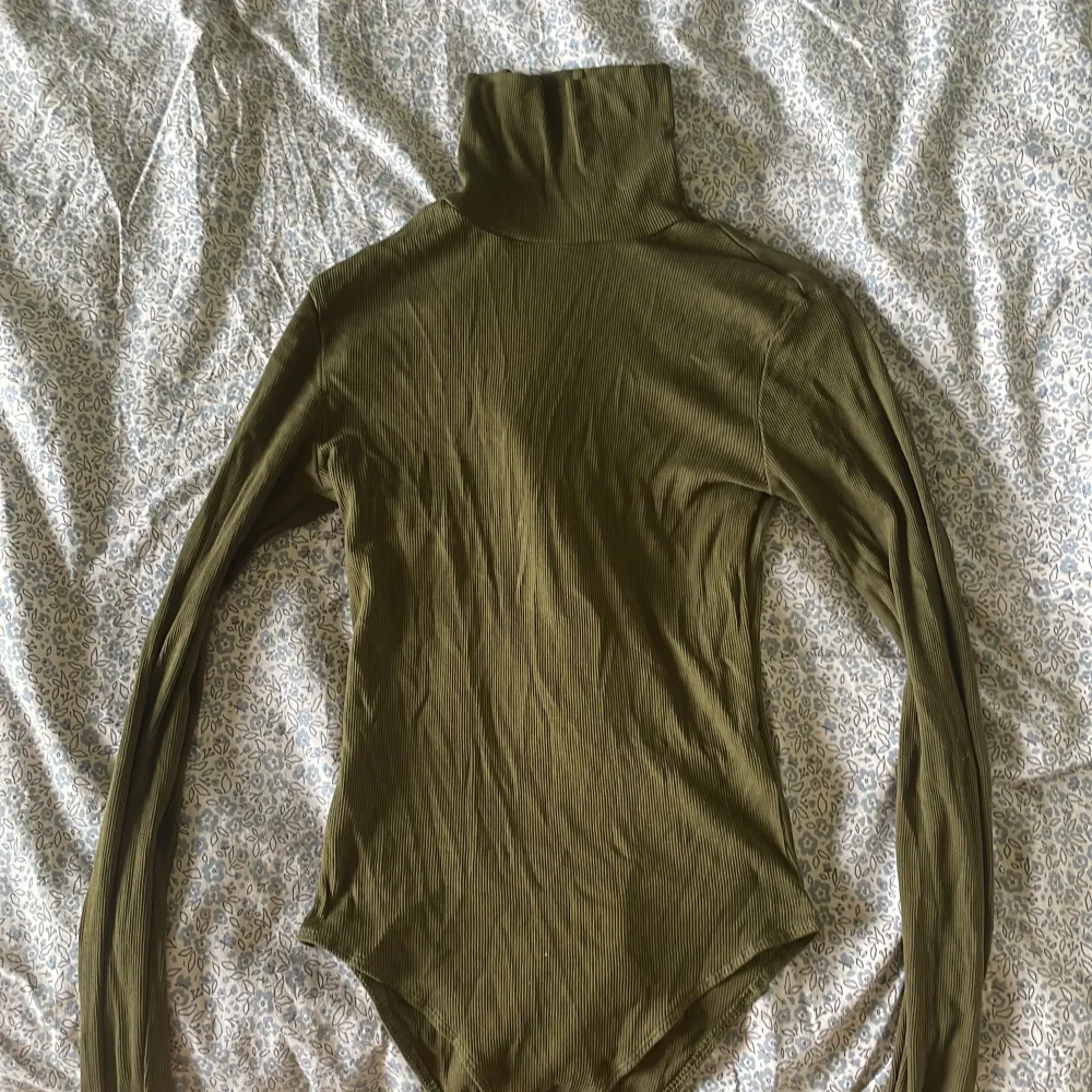 Säljer en snygg olivgrön ribbad Bodysuit från H&M. Den har en tight passform och långa ärmar, perfekt för höst och vinter. Materialet är mjukt och stretchigt, vilket gör den superbekväm att ha på sig. Perfekt för att styla med jeans eller kjol! Jag har använt den 1 gång . 💚. Toppar.