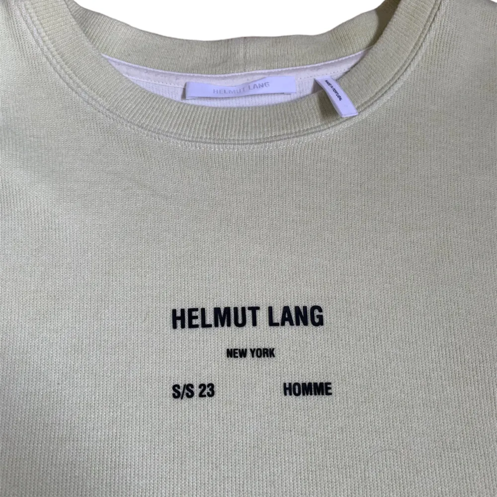 Säljer en stilren beige t-shirt från Helmut Lang med tryck på bröstet. T-shirten har en normal passform och är kortärmad, perfekt för vår och sommar. Materialet känns mjukt och skönt mot huden.. T-shirts.