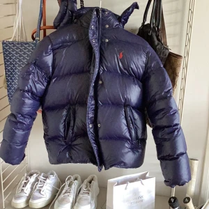 Blå Ralph lauren jacka - Säljer denna Ralph lauren jacka som jag inte andvänder längre. Den är i väldigt bra skick förutom en lapp som nästan har gått av. Den har 3 fickor, 2 utanpå och 1 inuti. Kan skicka fler bilder privat.