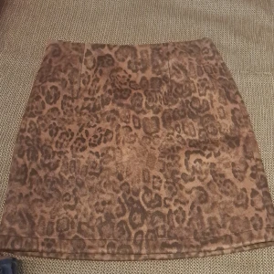 Leopardmönstrad kjol med dragkedja - Säljer en supercool leopardmönstrad kjol i brun nyans. Kjolen har en dragkedja baktill och är perfekt för en utekväll eller fest. Den är i ett mjukt material som känns skönt mot huden. 100% nytt. 