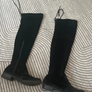 Svarta overknee stövlar i mocka - Säljer ett par snygga svarta overknee stövlar i mocka. De har en låg klack och är perfekta för höst och vinter. Stövlarna har en stilren design och passar både till vardags och fest.