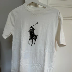 Polo Ralph Lauren T-shirt. - Oanvänd Polo Ralph Lauren T-shirt i storlek 160.