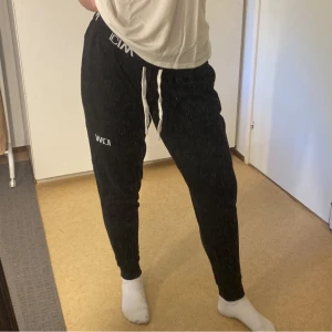 Svarta mjukisbyxor från ICANIWILL - Säljer ett par svarta mjukisbyxor från ICANIWILL. De har en bekväm passform med snörning i midjan och elastiska muddar vid bensluten. Perfekta för en avslappnad dag hemma eller lätt träning. Byxorna har också fickor på sidorna för extra funktionalitet. nypris 699kr