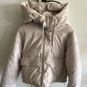 BEIGE VINTERJACKA  - Super fin och skön vinterjacka från pull&bear.  Stor och mysig luva. Normal längd men går att göra kortare med dragsko. 