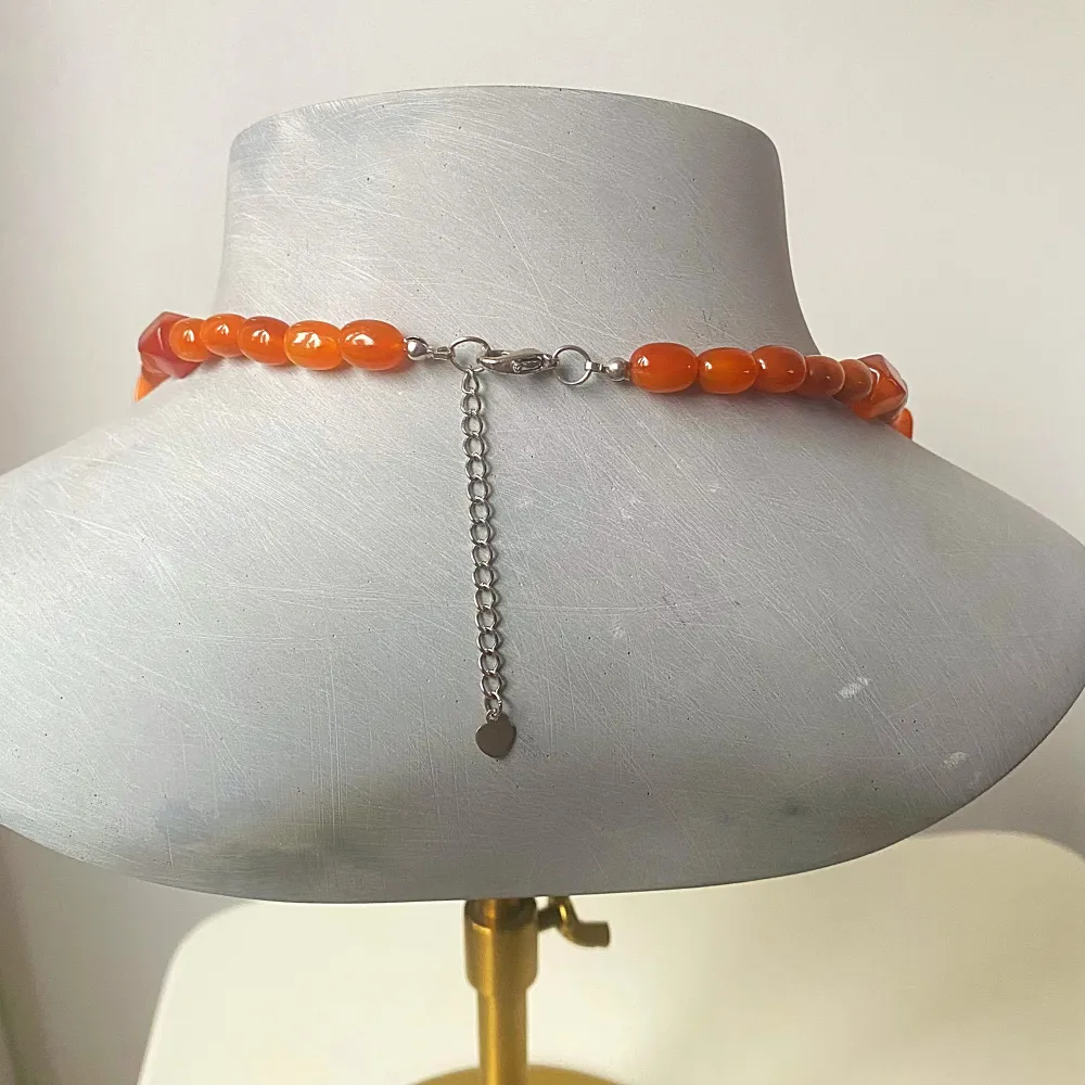 Snyggt långt  halsband med flera rader av små pärlor i orange och bruna nyanser. Halsbandet har en justerbar kedja baktill för perfekt passform. Perfekt för att liva upp en outfit med sina varma färger och unika design. Passar både till vardags och festliga tillfällen!. Accessoarer.