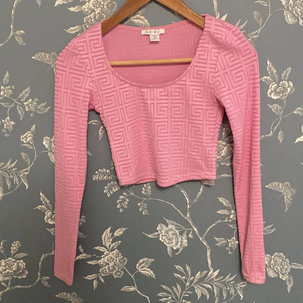 Säljer en superfin rosa U ringad och magtröja/croppad topp från Amisu i storlek XS. Den har ett coolt geometriskt mönster och är gjord av mjuk polyester med lite stretch. Perfekt för både vardag och fest! 💖 . Toppar.