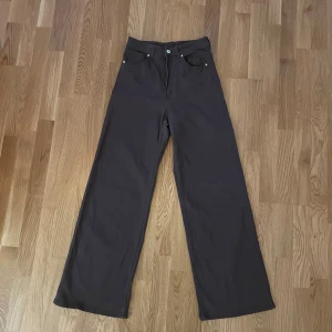 Bruna vida jeans - Säljer ett par bruna vida byxor i nyskick från H&M i storlek 38 M. De är högmidjade och har en klassisk femficksdesign. Ungefär 108 cm lång, passar bättre långa tjejer.