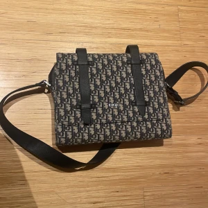 Dior postman bag - Fits macbook pro in n essentials in the small pockets inside the bag. The belt on the bag is short so it did not look as good on a really tall person, so recomended for a shorter person