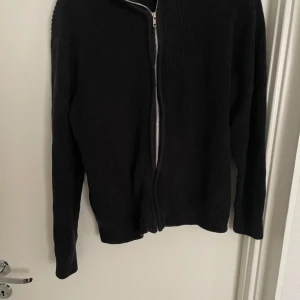 Svart tröja med dragkedja - Säljer en stilren svart tröja med dragkedja. Perfekt för både vardag och lite kyligare dagar. Tröjan har långa ärmar och en enkel design som gör den lätt att matcha med andra plagg. Passar bra för höst och vinter.