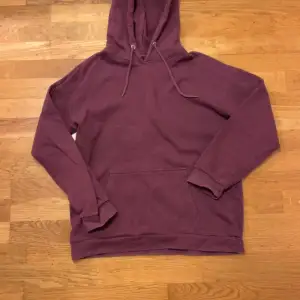 Vinröd hoodie från Pier One med magficka. Den har en klassisk design med dragsko i huvan och ribbade muddar vid ärmslut och nederkant. Använd ett par gånger, inga skador. Tvättettiketten är avklippt