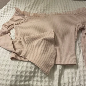 Beige/rosa offshoulder topp från Forever 21 - Säljer en superfin beige/rosa offshoulder topp från Forever 21. Den är ribbad med volangdetaljer längs kanten och har långa ärmar. Perfekt för både vardag och fest! 🥰