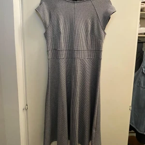 Klänning - Säljer en  svartvit rutig klänning från H&M i storlek M. Klänningen har en klassisk passform med korta ärmar och en dragkedja i ryggen. Oanvänd.