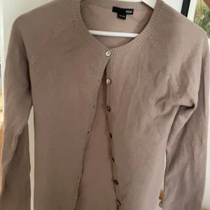 Beige kofta från H&M - Säljer en stilren beige kofta från H&M i storlek 32-34. Den är i nyskick och har långa ärmar med knappar framtill. Perfekt för både höst och vår, och passar till många olika outfits. Supermysig och lätt att matcha! 🌟