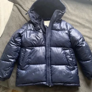 Blå puffer jacka  - Lånade bilder från förra säljaren!!❤️Supervarm jacka i äldre modell från hm. I stl xs men skulle säga att den passar S/M då den är väldigt oversized. Den är mörkblå och liite glansig. Har ett litet hål vid luvan och två små små fläckar inuti jackan, ena syns på sista bilden. Skriv gärna vid frågor eller bilder💕