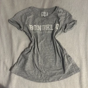 Grå t-shirt från Bondelid - Säljer en grå t-shirt från Bondelid med texten 'Modern Classics' tryckt på framsidan. T-shirten har korta ärmar och är tillverkad i ett mjukt bomullsmaterial. Perfekt för en avslappnad stil.