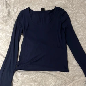 Mörkblå långärmad topp från Gina Tricot - Säljer en stilren mörkblå långärmad topp från Gina Tricot. Toppen har en rund halsringning och är tillverkad i ett mjukt material som ger en skön passform. Perfekt för en enkel och snygg look.