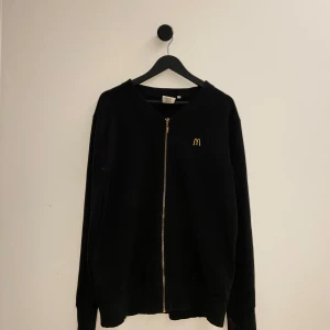 McDonalds zipup  - Säljer en svart zip-tröja från McDonald's Professional Workwear Edition. Tröjan har en gul broderad logotyp på bröstet och en dragkedja framtill. Perfekt för dig som gillar unika plagg med en twist! Skön till lalliga o soft outfits som sticker ut. Storlek L men passar M. Hör gärna av er vid flera frågor eller funderingar😅🤣