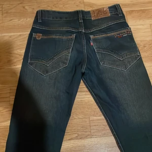 Mörkblå jeansbyxor från Lee - Säljer snygga mörkblå jeans med klassisk femficksdesign och kontrastsömmar från Lee. Jeansen är i storlek W29. Där är inprincip oandvänd. Priset kan diskuteras.🫶