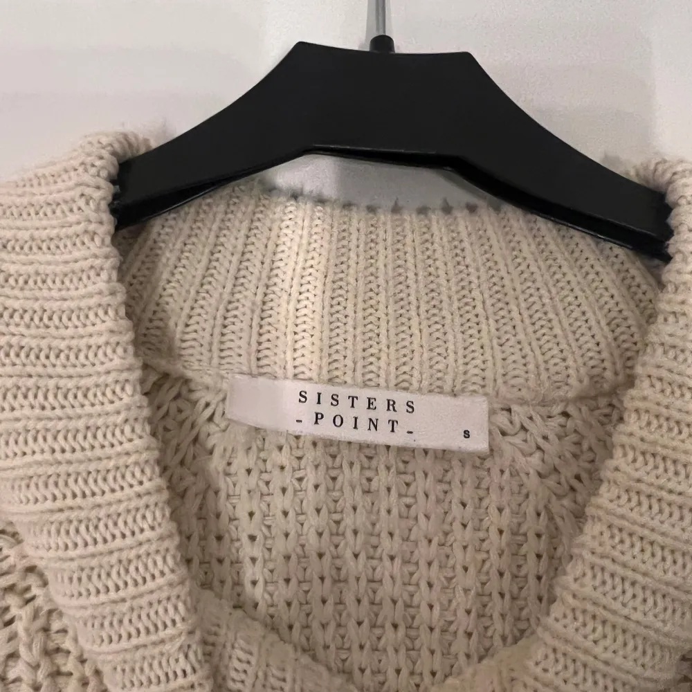 Säljer en mysig stickad tröja från Sisters Point i beige med svarta ränder. Tröjan har en avslappnad passform och långa ärmar, perfekt för kyligare dagar. Den är ribbad vid halsen och ärmsluten för extra komfort.. Neuletakit & Villapaidat.