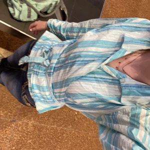 Blå och vit randig blus - Snygg blå och vit randig blus med knyt i midjan. Blusen har långa ärmar med skrunsh detalj och en klassisk krage. Skriv för mer detaljerade bilder🔥🙏🏻🩷