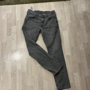 Grå jeans från Levi's - Snygga grå Levi's 511 jeans med en klassisk design. De har en normal passform och är tillverkade i slitstarkt denim. Perfekta för en stilren look med fem fickor och knappgylf. Priset är diskuter bar vid snabb affär 