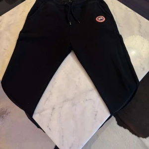 Svarta mjukisbyxor från Canada Goose - Snygga svarta mjukisbyxor från Canada Goose med broderad logotyp på sidan. Strl S