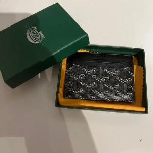 Svart kortfodral - Snyggt svart kortfodral med ett ikoniskt mönster i grått och vitt. Perfekt för att hålla dina kort organiserade. Kompakt och stilrent designad för att passa i fickan. Förpackning ingår 