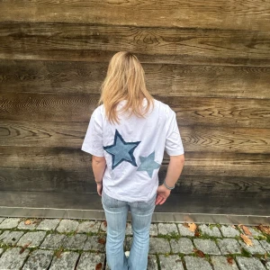 T-shirt med jeansstjärna  - Snygg vit t-shirt med stjärnor på ryggen i jeanstyg. T-shirten är i skönt material och har en boxig form. Så unik tröja som passar till allt och alla. teezy_uf på instagram och tiktok