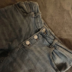 Blå jeans med knappar - Snygga blå jeans med knappar framtill. De har en klassisk design med fem fickor och en bekväm passform. Perfekta för en avslappnad stil.❤️Storlek: 164cm