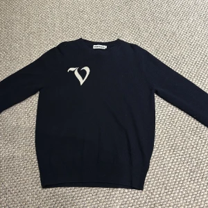 Svart tröja från vonstudio - Snygg mörk blå tröja från vonstudio med ett stilrent vitt tryck på bröstet. Tröjan har en klassisk design med rund hals och långa ärmar. Perfekt för en stilren look. Cashmere blandning. Har även noppror på vänster sida men inget som syns tydligt, köpt för 700kr, skriv vid minsta fundering. Sitter mer som M/S