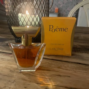 Poême Eau de Parfum från Lancôme - Elegant parfymflaska med gyllene lock och en varm, bärnstensfärgad vätska. Förpackningen är i en distinkt gul färg med svart text. Perfekt för den som söker en klassisk och sofistikerad doft.