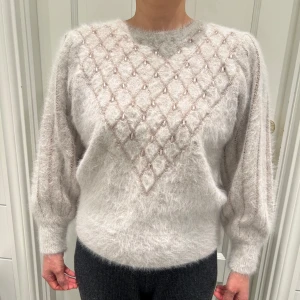 Vit/beige angora tröja med pärldetaljer - Säljer en mjuk och fluffig vit/beige tröja i 80% angora med unika pärldetaljer i ett diamantmönster på framsidan. Ärmarna är 56cm från axeln. 3 stygn på axeln är sydda pga att en tråd gick av, men det påverkar inte utseendet. Säljer då ärmarna är för korta för mig.💗Pris går att diskutera.
